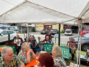 Die Musiker des "Steinachtaler Akkoroen Clubs" machen Musik. Im Vordergrund sind einige Zuschauer an Bierbänken sitztend.